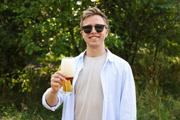 Fototapeta premium Young man with glass of beer outdoors