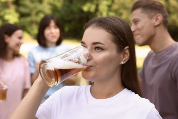 Group of happy friends having fun and drinking beer outdoors, selective focus