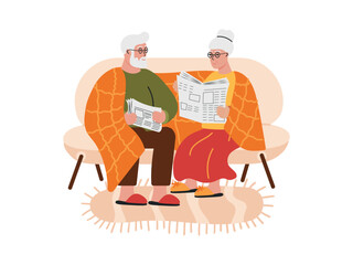 Elderly couple sitting on the sofa and reading newspapers, wrapped in a warm cozy blanket