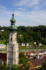 Church tower with green dome roof and clock in Burghausen, Bavaria, Germany, overlooking the river and colorful old town houses, photographed in 2024.