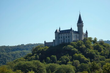 Fototapeta premium Majestic castle perched atop a lush green hill under a clear blue sky