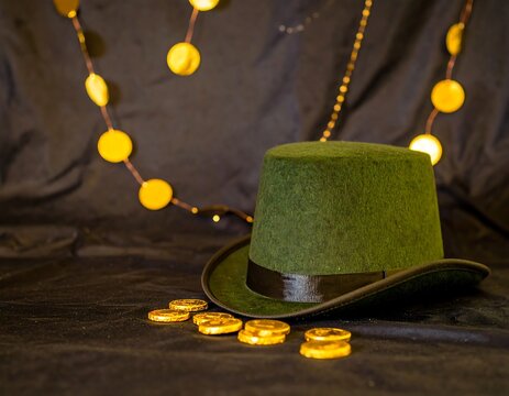 A green top hat with gold coins and a garland of gold beads on a dark background.