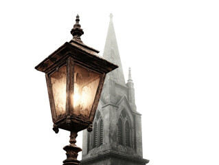 An old ornate and rusty cast iron street lamp with a warm glowing light and intricate finial.