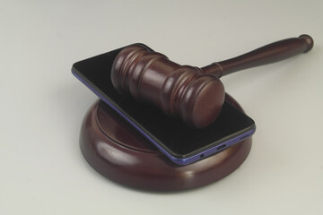 Smartphone and wooden judge gavel on grey background