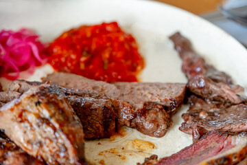 Grilled beef steak, tomato sauce and fresh salad on a wooden table