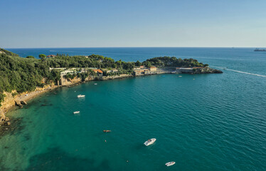 Fototapeta premium An aerial view of a scenic bay and coastline in the Gulf of Poets near Lerici, with turquoise water, a rocky shore, and lush green cliffs.