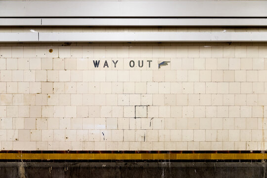 Old tiled wall with a weathered 'Way Out' sign in an underground train station