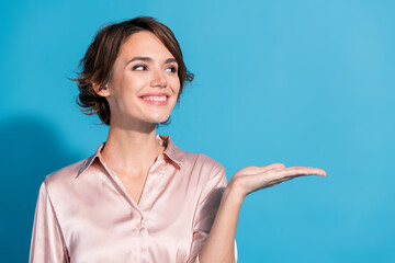 Young woman in pink satin blouse gesturing with hand against blue background