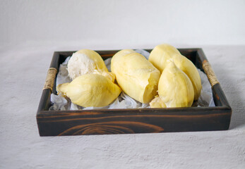 A yellow durian that has been peeled off to reveal the tasty yellow flesh of the durian. Durian fruit on wooden basket