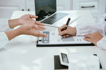 A doctor consults with a patient in a healthcare office, reviewing documents and providing medical advice, diagnosis, and treatment during a professional hospital or clinic appointment.