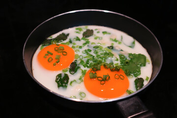fried egg or sunny side up egg with vegetable topping in a pan