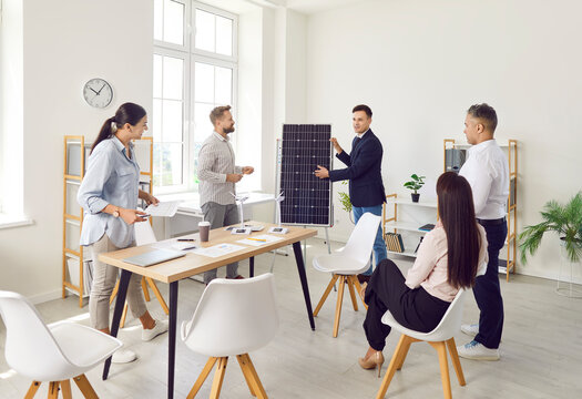 Positive businessman is consulting a team of coworkers and customers about solar panels and renewable energy during a meeting in the office. The consultation focuses on sustainable energy solutions. - Powered by Adobe