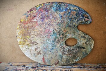 Colorful artist palette. Used palette with paints close-up. Artist palette stands against the wall.