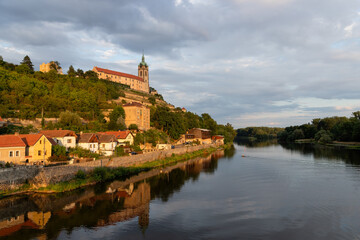 Obraz premium The view of an historical town and renaissance Melnik castle on the hill above Labe and Vltava river confluence during a vibrant golden hour. Central Bohemia, Czech Republic