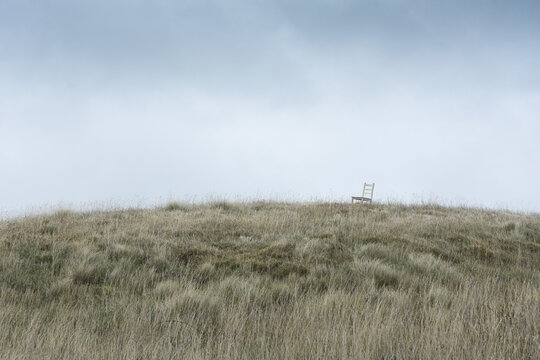 Chair on grassy hill with grey sky