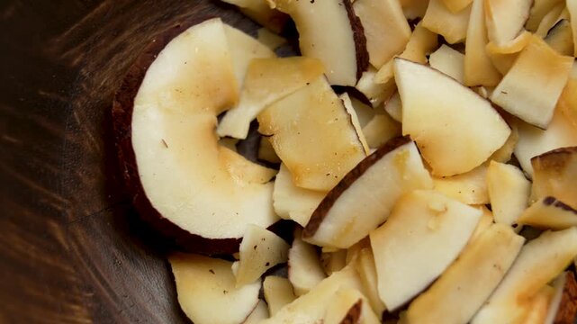 Dried coconut chips or coco shavings in wooden bowl. Vitamin snack. Top view. Rotation