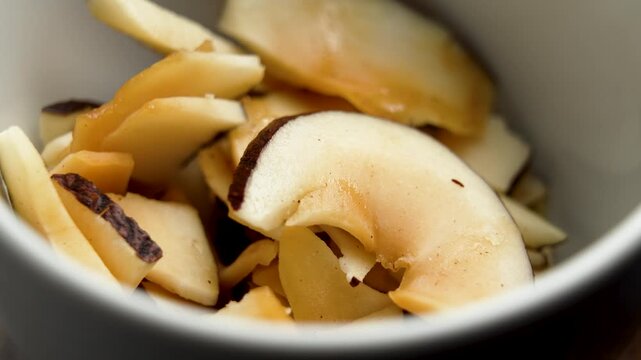 Dehydrated coconut chips in white ceramic bowl. Dried nutritional snack. Rotation