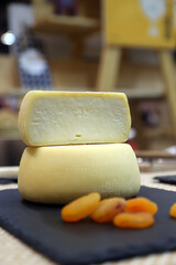 quesos de oveja entero y partido por la mitad sobre una tabla de pizarra con frutos de dulces escarchados