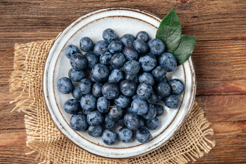 Blueberries on a plate. wooden table background. summer berry harvest. table top view