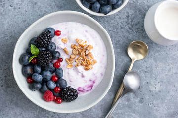 Blueberry yogurt with berry fruits topping on a wooden table background, top view
