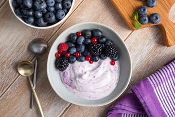 Blueberry yogurt with berry fruits topping on a wooden table background, top view