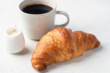 French croissant and black coffee with cream on grey stone background. Cafe menu concept