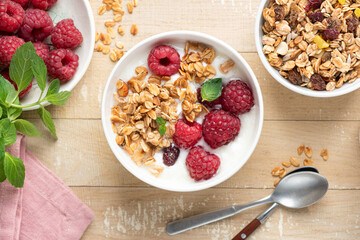 Granola bowl with yogurt and raspberries on wooden table background, closeup view, healthy diet meal
