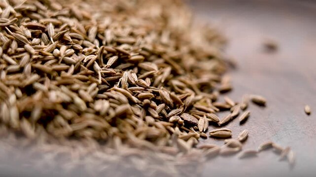 Aromatic cumin seeds falling into wooden rustic bowl. Organic Asian spice. Macro. Slow motion