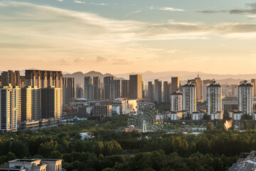 Sunset view of modern city buildings with green park in foreground