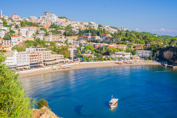 A sunny view of Mala Plaža in Ulcinj, Montenegro, with sandy shores, coastal buildings, and a boat floating in the calm blue Adriatic Sea.