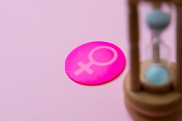A wooden hourglass with the female gender symbol. Women's health, menopause, aging concept. Copy...