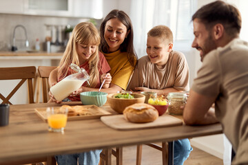 Happy family enjoying while having breakfast in dining room.	