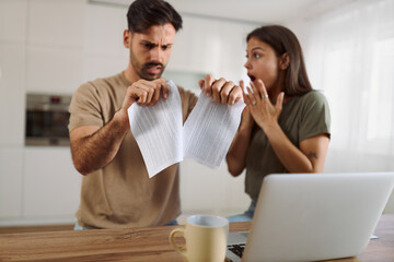 Close up of a couple tearing their tax bill at home.