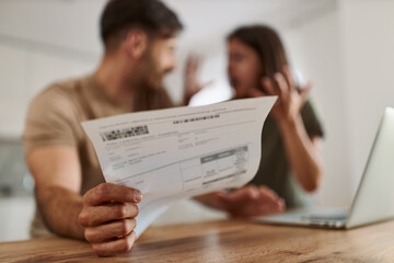 Close up of young couple having problems with paying their bills over a computer at home.