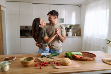 Happy mid adult couple having fun while dancing at dining room