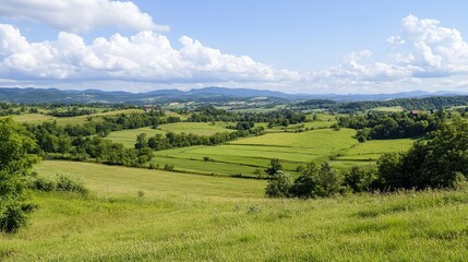 Obraz premium A breathtaking landscape features rolling green hills under a blue sky with fluffy clouds, ideal for nature-themed projects, travel brochures, or relaxation-related content,