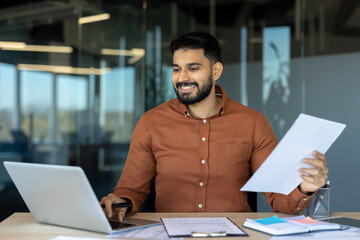 Business professional working with documents and laptop in a modern office setting