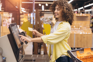 Woman paying using self checkout machine in supermarket