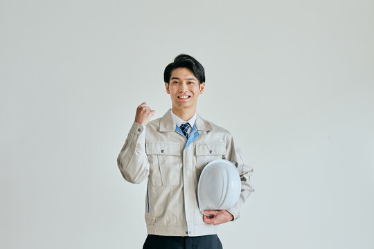 ガッツポーズをする作業服姿の若い男性