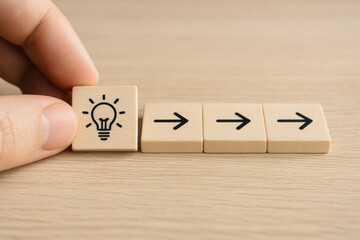 Idea concept with wooden blocks showing light bulb and arrows on wooden table