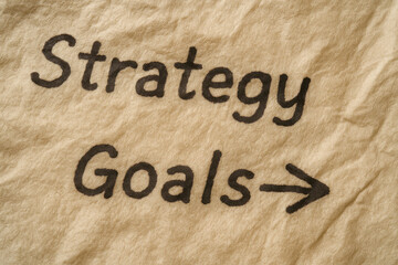 Strategy goals written on textured paper with arrow pointing forward