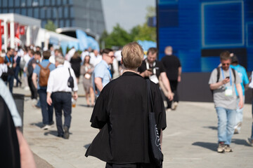 Group of individuals walking through an outdoor public space during a bustling daytime event
