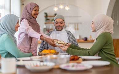 Muslim big family sharing traditional meal together around dining table wearing hijabs and kufi in cultural love, ramadan iftar celebration, eid al-fitr festive, halal meal gathering food culture