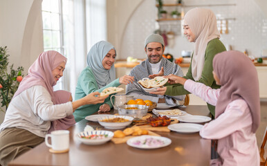 Muslim big family sharing traditional meal together around dining table wearing hijabs and kufi in cultural love, ramadan iftar celebration, eid al-fitr festive, halal meal gathering food culture