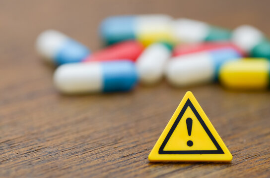 Warning Sign with Blurred Pills &mdash; Caution on Medication Risks and Side Effects