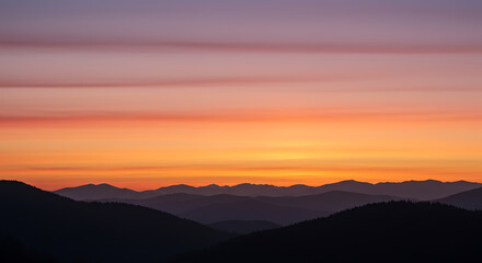 Obraz premium Stunning sunset over mountain range with vibrant orange and gold hues