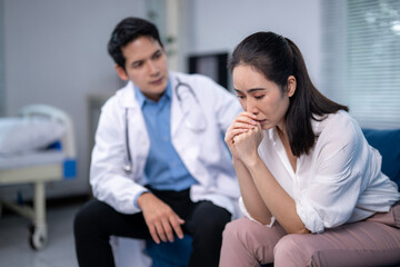 A woman sits on a couch in a hospital room, crying