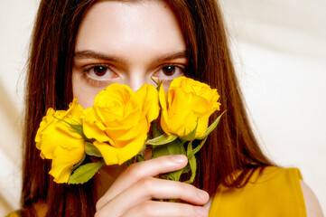 Close-up of brunette, dark eyes close-up, with a bouquet of yellow roses in her hands, near her face