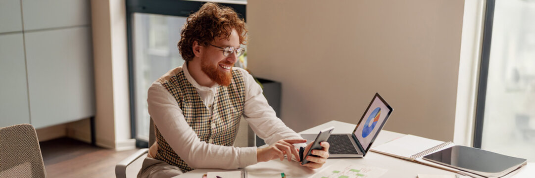 An individual, highly focused, engages with a smartphone while comfortably seated at a stylish office desk setup