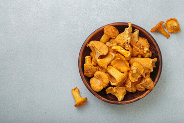 Fresh chanterelle mushrooms in a rustic wooden bowl, on a gray background, a warm and inviting autumnal scene perfect for culinary uses, copy space